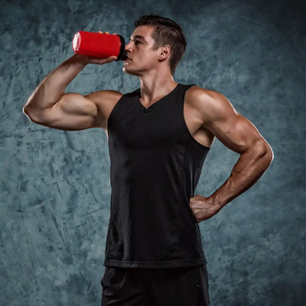 Homme musclé buvant d'une bouteille rouge.